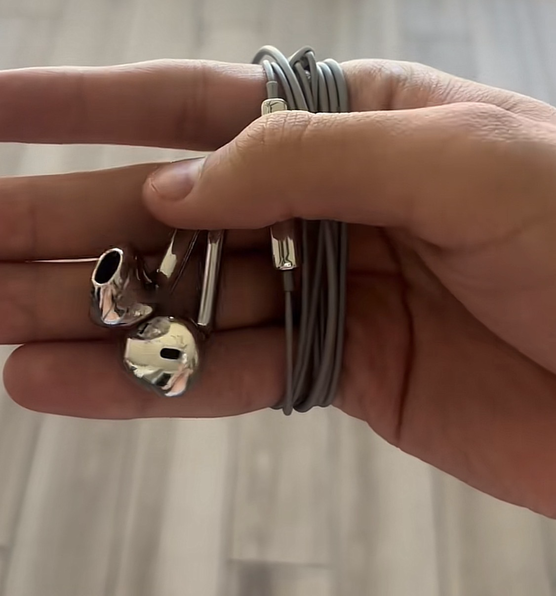 Customer holding Phantom Platinum earphones with cable coiled around their hand
